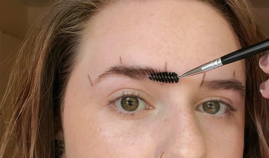 Brushing brows with spoolie for shaping